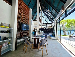 A modern interior with a dining area, a TV, and a view of the outdoors. - Casalay Boutique Villas & Dive (Puerto Galera)