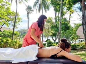 A massage therapy session in a tropical setting with a view of a body of water and lush greenery. - Casalay Boutique Villas & Dive (Puerto Galera)