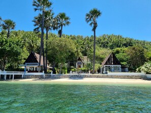A beachfront property with multiple buildings, a clear view of the ocean, and a lush green backdrop. - Casalay Boutique Villas & Dive (Puerto Galera)