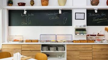 Una barra de desayuno con un menú en pizarra, frascos de condimentos y una variedad de productos para el desayuno.