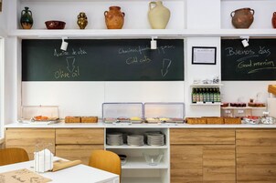 Una barra de desayuno con un menú en pizarra, frascos de condimentos y una variedad de productos para el desayuno.