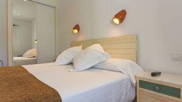A hotel room with a bed, bedside table, and a mirror.