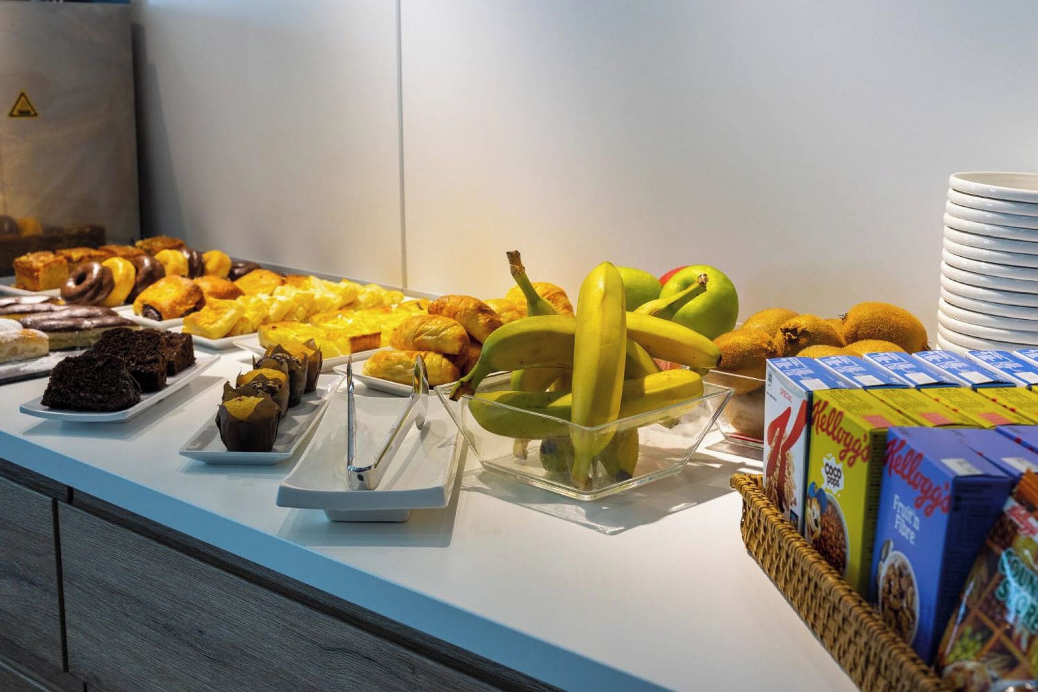 Un bufé con distintos tipos de alimentos, incluyendo pasteles, frutas y cajas de cereales.