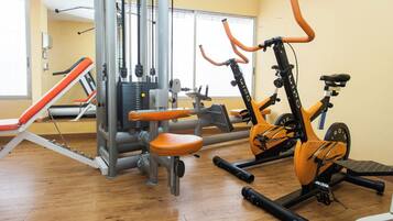 A gym with exercise equipment, a wall clock, and a window.