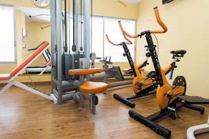 A gym with exercise equipment, a wall clock, and a window.