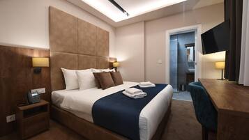 A hotel room with a large bed, bedside lamps, a desk, and a TV.