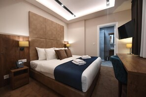 A hotel room with a large bed, bedside lamps, a desk, and a TV. - Hammeum Hotel (Prokuplje)