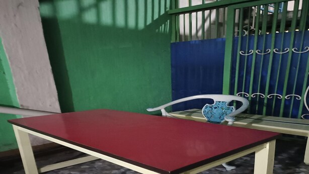 Una mesa roja con una silla blanca frente a una pared verde.