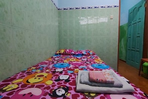 Una habitación pequeña con una cama, un armario verde y una pared de azulejos.