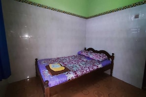 Una habitación pequeña con cama individual, una colcha estampada, cabecera de madera y suelo de baldosas.