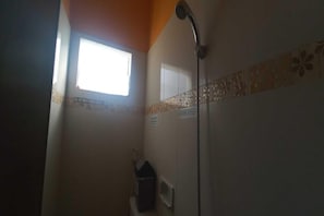 Un baño con ducha, ventana y toallero.