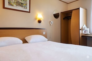 A hotel room with a bed, a wall-mounted lamp, a coat rack, and a mirror. - The Galleon Hull (Hull)