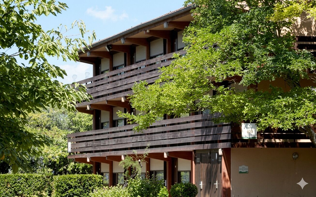 A multi-story building with balconies, surrounded by greenery.