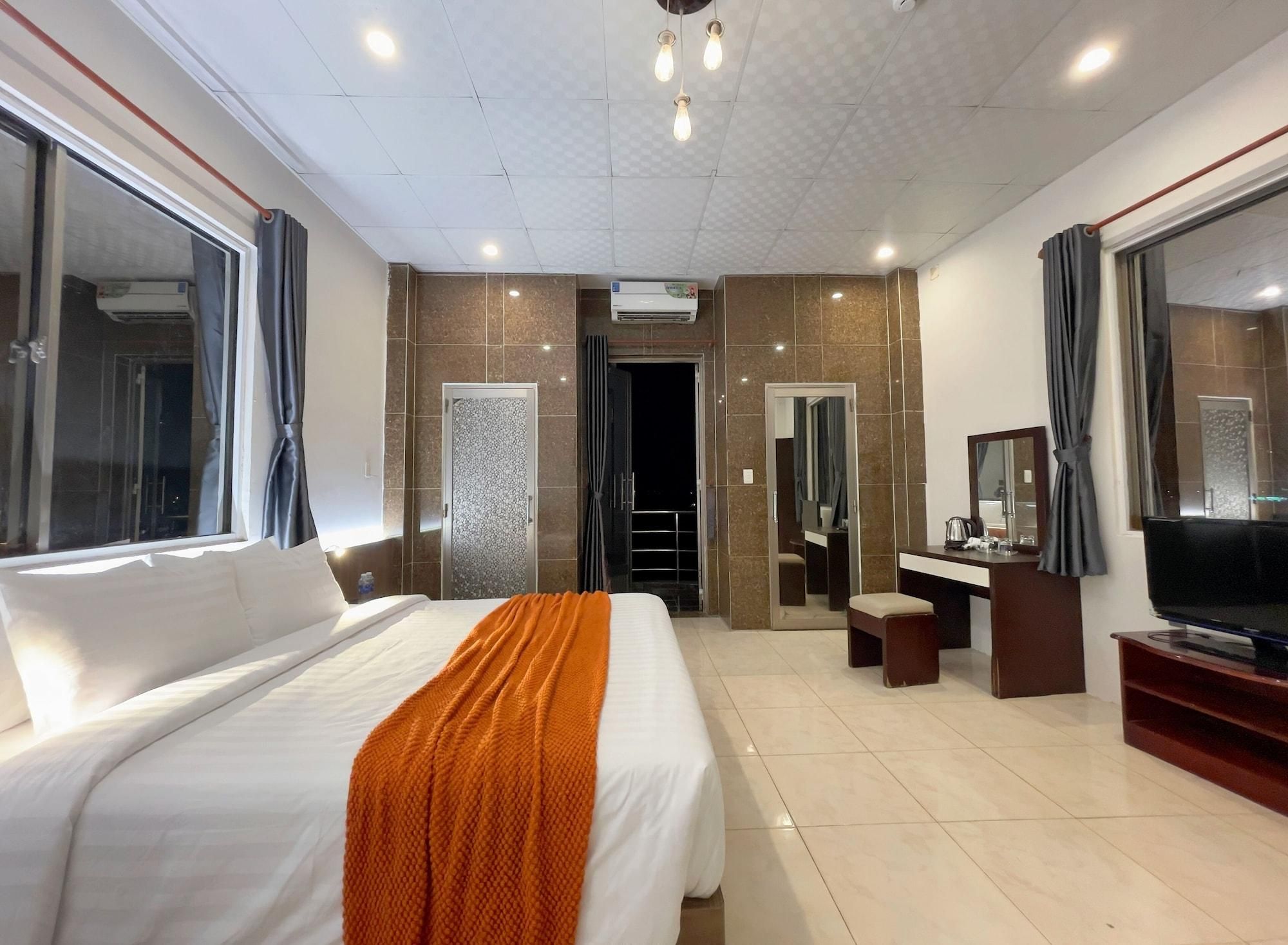 Une chambre d’hôtel avec un grand lit, une télévision, un bureau et une salle de bain visible à travers une porte ouverte.
