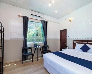 A hotel room with a bed, a table with chairs, an air conditioning unit, and a window with curtains. - Front Beach Hotel By Joi Hospitality (Vung Tau)
