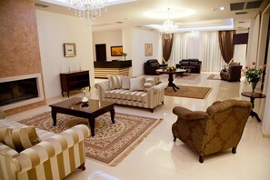 A spacious living room with a fireplace, sofas, a coffee table, and a chandelier. - Filokalia Hotel (Ioannina)