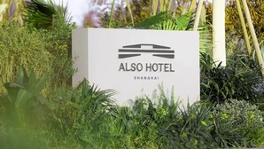 A sign for the ALSO HOTEL in SHANGHAI, surrounded by lush greenery. - Shanghai Also Hotel (Shanghai)