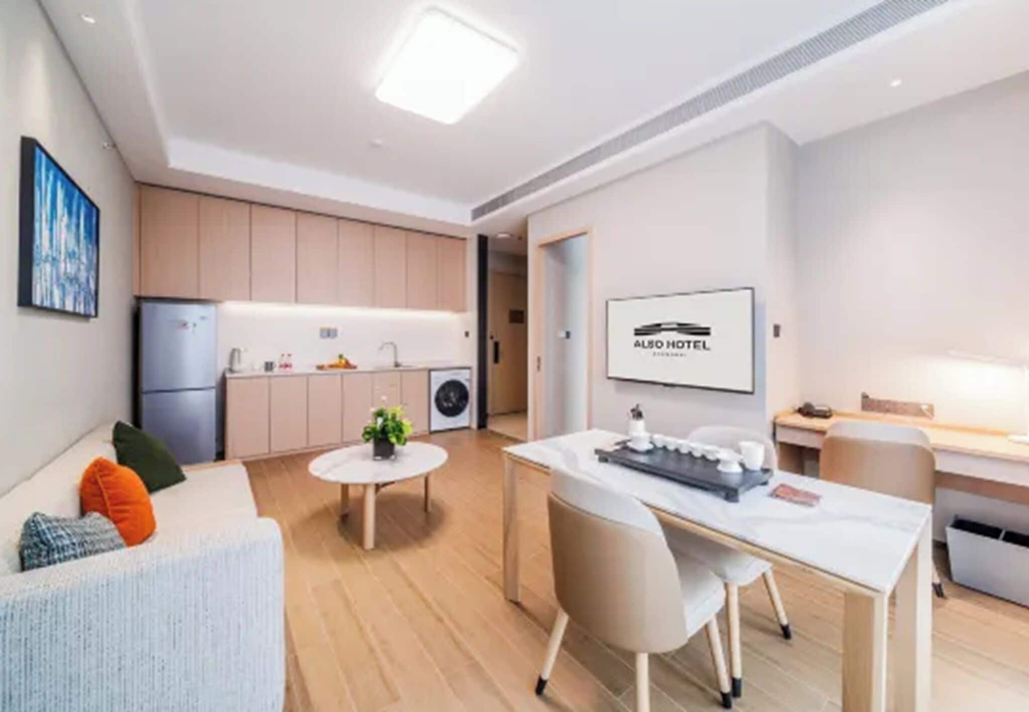 Moderni hotellihuone, jossa on pieni keittiö, ruokailutila ja oleskelualue.