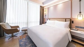 A hotel room with a large bed, a chair, a nightstand, and a lamp. - Shanghai Also Hotel (Shanghai)