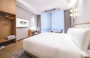 A hotel room with a bed, a desk, a chair, a wardrobe, and a window with curtains. - Shanghai Also Hotel (Shanghai)