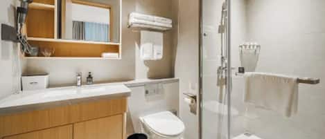 Een moderne badkamer met een douchecabine van glas, een toilet, een wastafel met spiegel en een handdoekrek.
