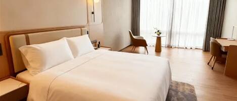 Ein Hotelzimmer mit einem großen Bett, einem Schreibtisch, einem Stuhl und einem kleinen Tisch mit einer Pflanze.