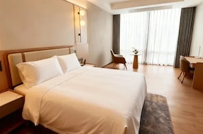 A hotel room with a large bed, a desk, a chair, and a small table with a plant. - Shanghai Also Hotel (Shanghai)