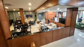 A hotel lobby with a reception desk, seating area, and a dining section. - Mahakam24 Residence (Jakarta)