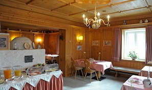 A wooden interior with a dining area, breakfast buffet, and a chandelier. - Hotel Hafnerwirt (Hallein)