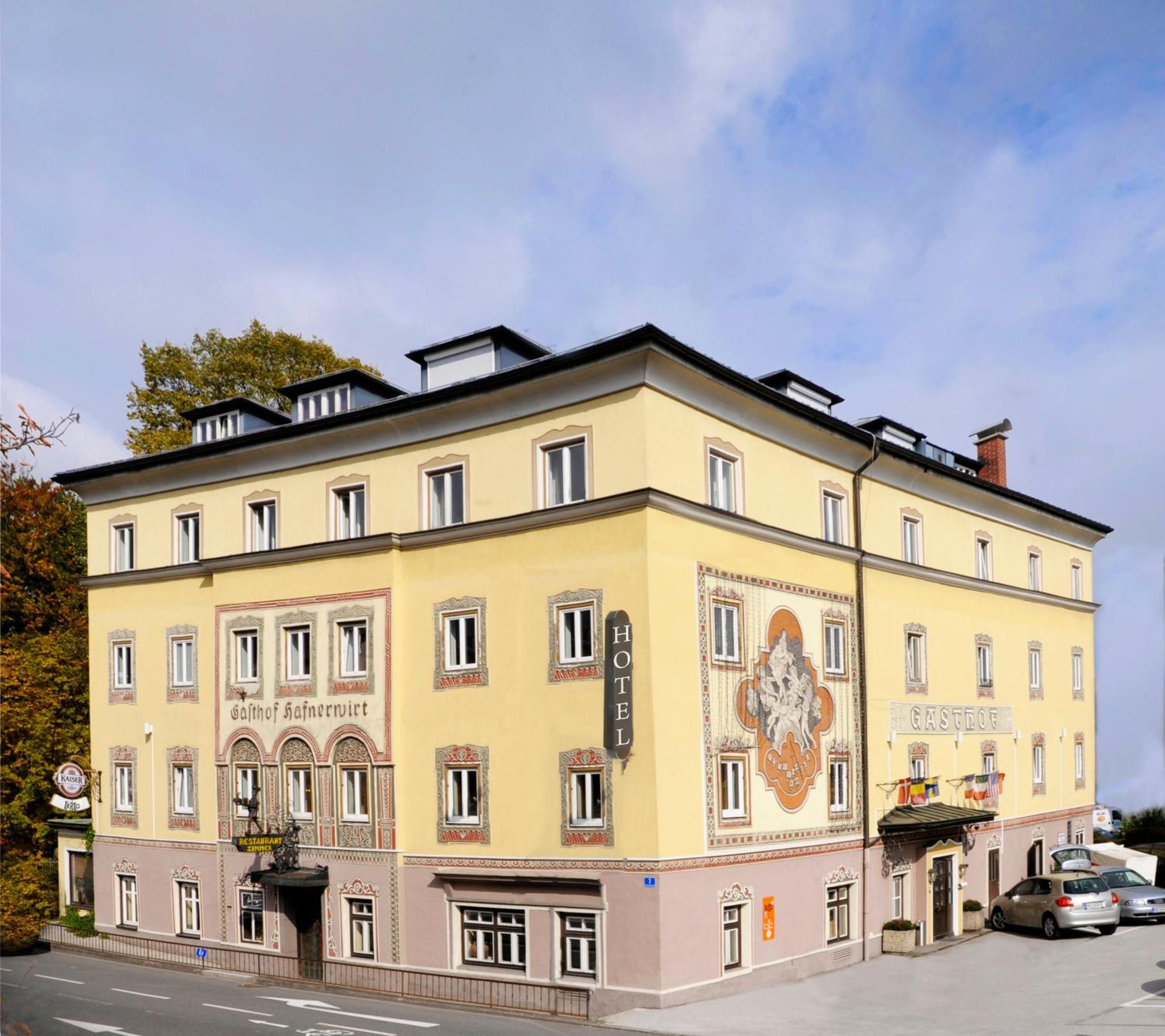 Ein mehrst öckiges Hotel im klassischen Baustil, mit einer gut sichtbaren Schilderung des Restaurants und einem großen Wappen an der Fassade.