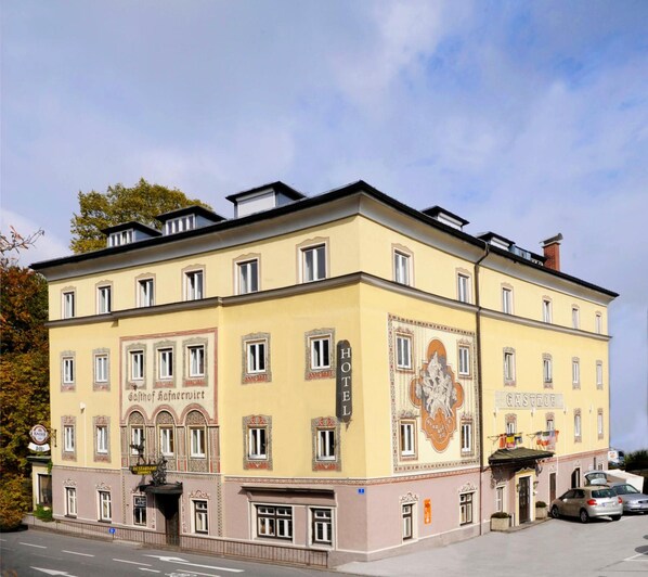 A multi-story hotel with a classic architectural style, featuring a prominent sign for the restaurant and a large emblem on the facade. - Hotel Hafnerwirt (Hallein)