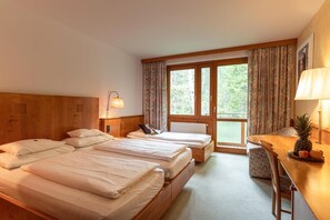 A hotel room with two beds, a desk, a chair, and a large window with curtains. - Hotel Restaurant Sv Drast Dreilv Ndereck (Arnoldstein)