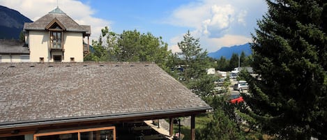 A building with a sloped roof, a covered outdoor seating area with tables and chairs, and a mountain backdrop.