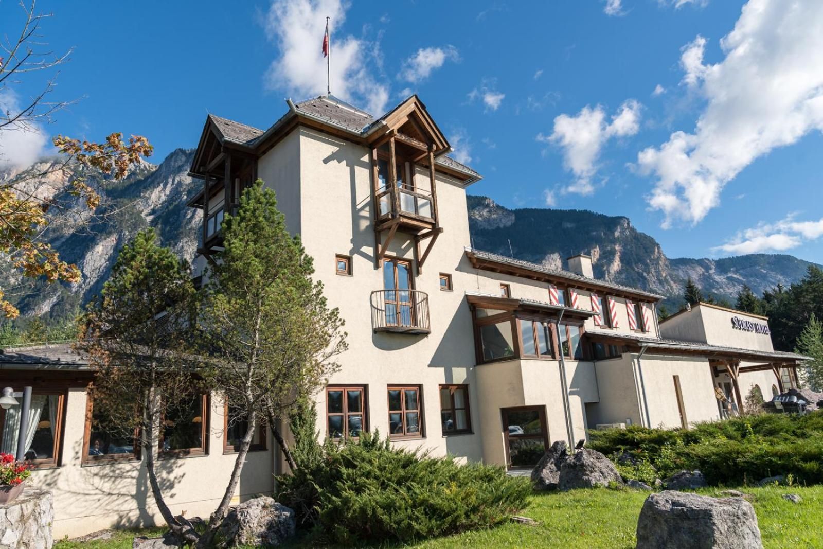 A mountain lodge with a balcony, a mountain view, and a sign reading 'Ski Resort'.