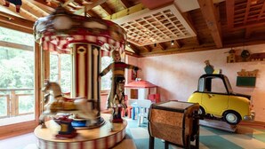 A room with a carousel, a yellow toy truck, and a checkered floor. - Hotel Restaurant Sv Drast Dreilv Ndereck (Arnoldstein)