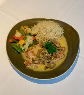 A plate with a piece of meat, rice, and mixed vegetables. - Hotel Restaurant Sv Drast Dreilv Ndereck (Arnoldstein)