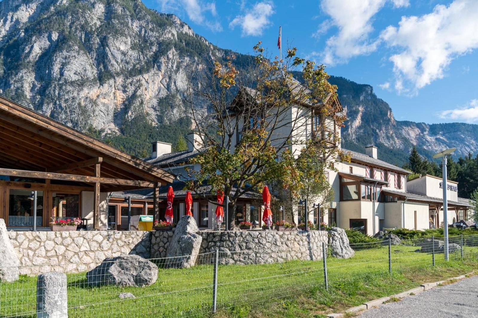 A mountain lodge with stone walls, wooden beams, and red umbrellas.