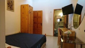 A bedroom with a bed, wooden wardrobe, a small table with a vase, and a TV mounted on the wall. - Park Hotel Amfora (Sofia)