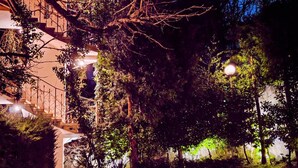A nighttime outdoor area with a paved walkway, trees, and a building with illuminated windows. - Park Hotel Amfora (Sofia)