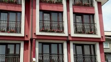 Un hotel de varios pisos con balcones, fachada roja y blanca, y un letrero que indica cercanía a Roma.