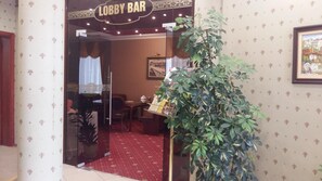 A lobby bar with a glass door entrance, a red carpeted floor, and a potted plant. - Central (Veliko Tarnovo)