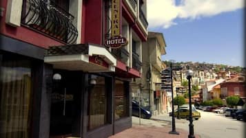 A hotel with a sign reading 'CENTRAL HOTEL' on the facade, a street view with parked cars, and a clear sky.