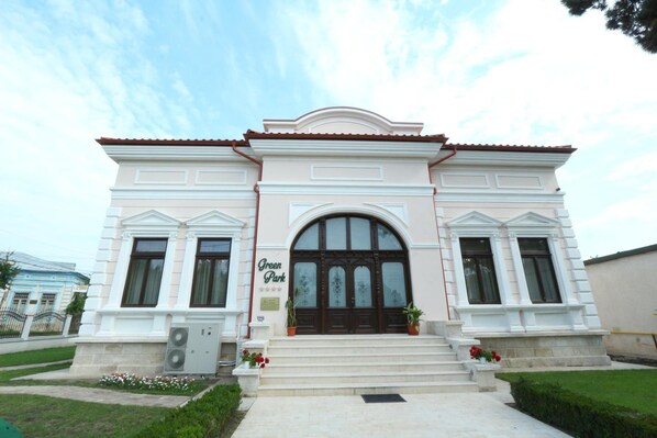 A building with a symmetrical facade, a central entrance with a large arched doorway, and a sign that reads 'Green Park'. - Green Park Boutique Hotel (Focsani)