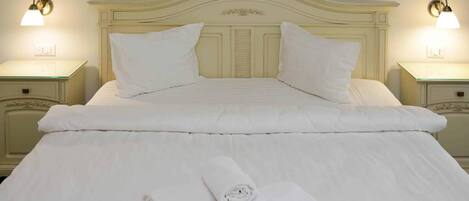 A neatly made bed with pillows and a rolled towel on a cream-colored headboard.