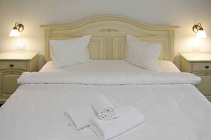 A neatly made bed with pillows and a rolled towel on a cream-colored headboard. - Green Park Boutique Hotel (Focsani)