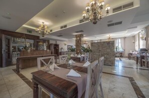A spacious hotel lobby with a reception desk, multiple dining tables, and a stone accent wall. - Orient Palace (Kobierzyce)