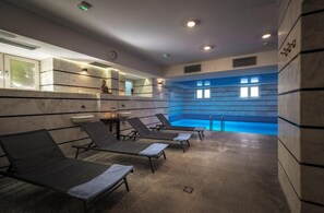 Zona de spa con hidromasaje, sillas de descanso y una estatua en la pared.