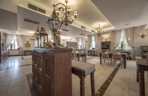 A spacious hotel lobby with a high ceiling, ornate chandeliers, and a central wooden table. - Orient Palace (Kobierzyce)