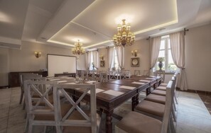 A conference room with a long table, multiple chairs, chandeliers, and a projector screen. - Orient Palace (Kobierzyce)