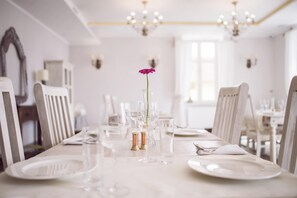 A dining table set with white plates, glasses, and cutlery, with a single flower centerpiece. - Orient Palace (Kobierzyce)